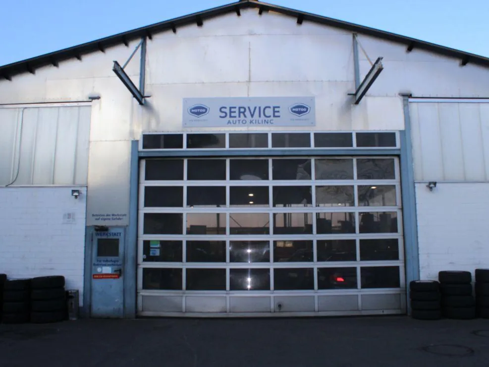Werkstatthalle von Auto Kilinc mit großem Rolltor und Service-Schild
